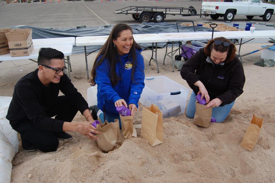 Dante Stevens, left, the Campus Activities Board vice president; Christina Holden, the CAB president; and Amanda Robles, the director of student engagement and campus life, fill sacks with sand on Dec. 1 in preparation for this weekend's luminarias display on the San Juan College campus in Farmington.