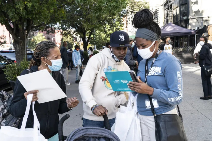 Census 2020 employees helps a New Yorker fill out a census form