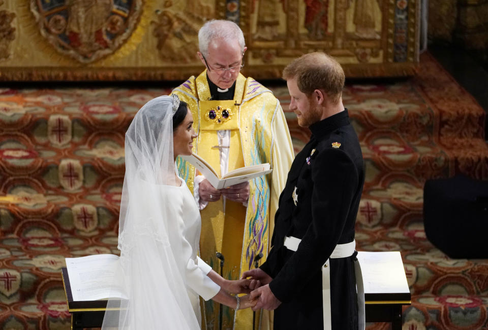 TOPSHOT - Britain's Prince Harry, Duke of Sussex (R) and US actress Meghan Markle (L) stand facing each other hand-in-hand before Archbishop of Canterbury Justin Welby (C) during their wedding ceremony in St George's Chapel, Windsor Castle, in Windsor, on May 19, 2018. (Photo by Owen Humphreys / POOL / AFP)        (Photo credit should read OWEN HUMPHREYS/AFP via Getty Images)