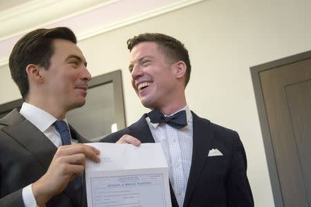 Rodrigo Zamora (L) and Ashby Hardesty show their marriage license to friends at the New York City clerk's office after their wedding in Manhattan in New York June 26, 2015. REUTERS/Brendan McDermid