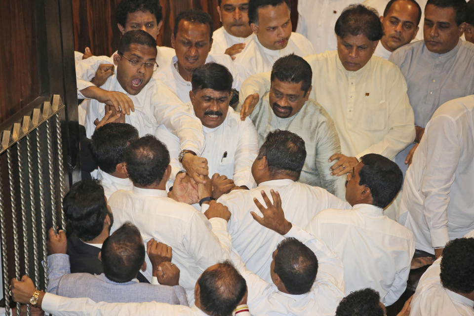 Sri Lankan Lawmakers fight in the parliament chamber in Colombo, Sri Lanka, Thursday, Nov. 15, 2018. Rival lawmakers exchanged blows in Sri Lanka's Parliament on Thursday as disputed Prime Minister Mahinda Rajapaksa claimed the speaker had no authority to remove him from office by voice vote. (AP Photo/Lahiru Harshana)