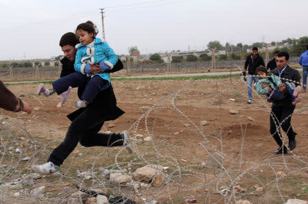 FILE PHOTO: Syrians jump over barbed wire as they flee from the Syrian town of Ras al-Ain to the Turkish border town of Ceylanpinar, Sanliurfa province, Turkey November 9, 2012. REUTERS/Stringer/File Photo