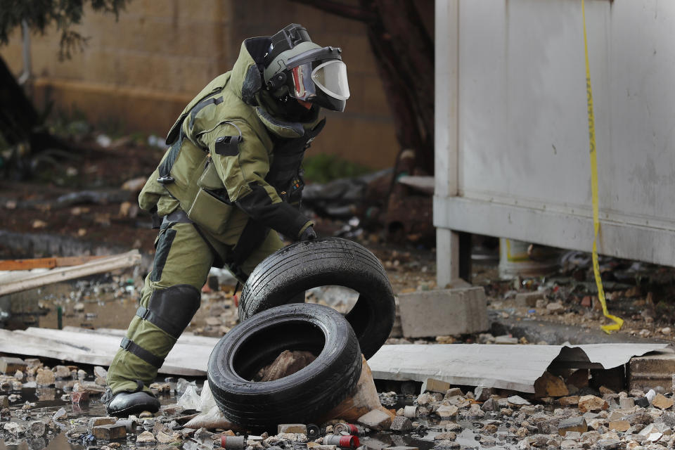 A Lebanese police bomb disposal expert prepares to destroy an unexploded hand grenade that was throw by protesters on Thursday night inside the parking of an official government office, during a protest against deteriorating living conditions and strict coronavirus lockdown measures, in Tripoli, Lebanon, Friday, Jan. 29, 2021. (AP Photo/Hussein Malla)