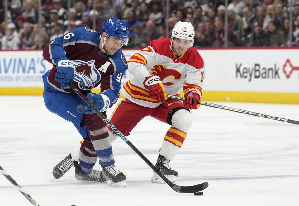 Colorado Avalanche right wing Mikko Rantanen, front, collects the puck as Calgary Flames center Yegor Sharangovich defends in the first period of an NHL hockey game, Monday, Dec. 11, 2023, in Denver. (AP Photo/David Zalubowski)