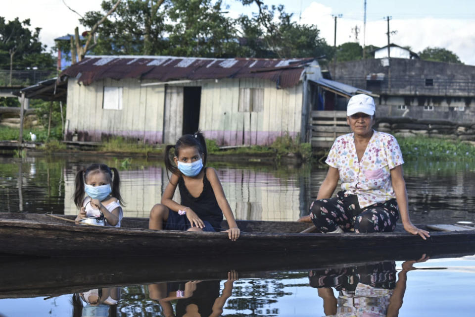 A woman and two girls wearing face masks, as a preventive measure against the spread of the novel coronavirus, COVID-19, sail at the Amazon river in Leticia, Colombia. Source: Getty Images