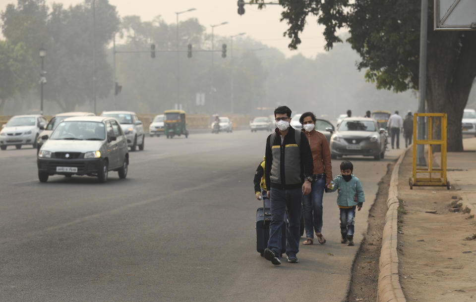 A family wears pollution masks and walk looking for a transportation a day after Diwali festival, in New Delhi, India, Thursday, Nov. 8, 2018. Toxic smog shrouds the Indian capital as air quality falls to hazardous levels with tens of thousands of people setting off massive firecrackers to celebrate the major Hindu festival of Diwali on Wednesday night. (AP Photo/Manish Swarup)