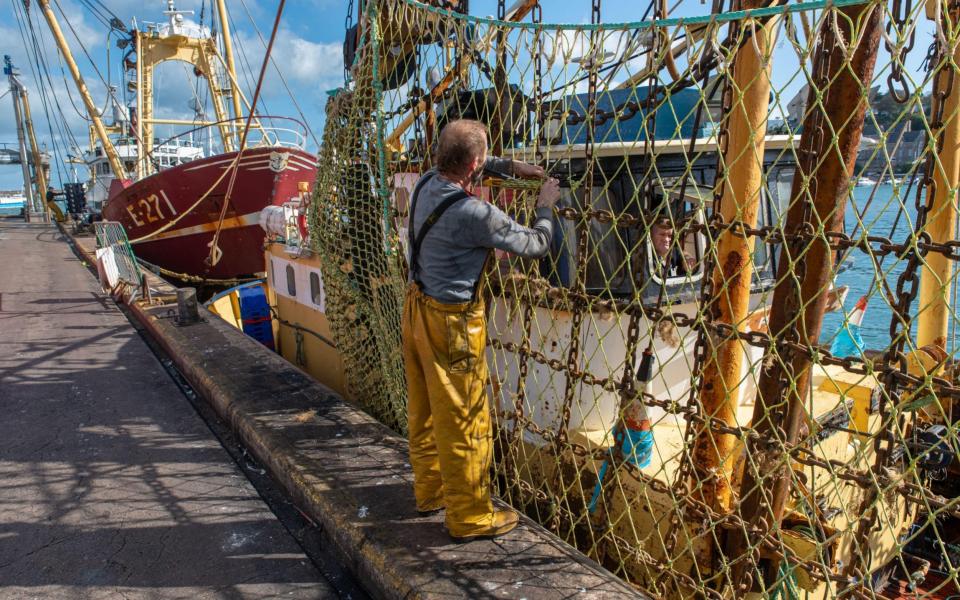 All at sea: mending the nets of the fishing vessel Pamela Jill in Brixham Harbour, Devon - lionel derimais/Alamy