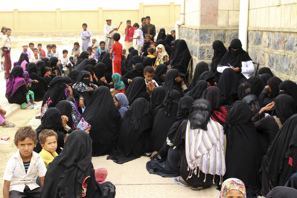 In this Aug. 25, 2018 photo, women wait with their children in front of the Aslam Health Center, in Hajjah, Yemen. Yemenis in the isolated pocket in the north have been reduced to eating boiled leaves from a local vine to stave off starvation, with no aid reaching many families who need it most. The situation in Aslam district is a sign of the holes in an international aid system that is already overwhelmed but is the only thing standing between Yemen’s people and massive death from starvation amid the country’s 3-year civil war. (AP Photo/Hammadi Issa)