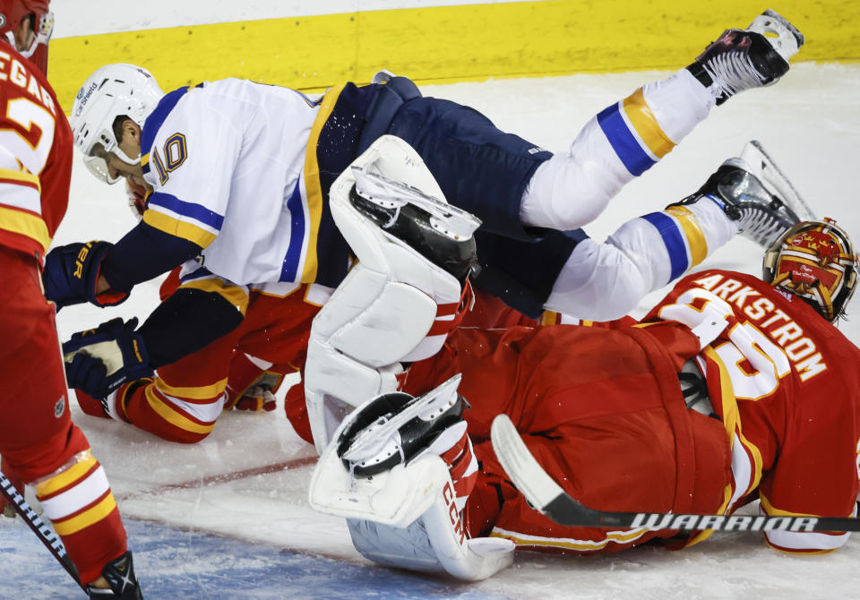 St. Louis Blues forward Brayden Schenn, left, crashes over Calgary Flames goalie Jacob Markstrom during the second period of an NHL hockey game in Calgary, Alberta, Thursday, Oct. 26, 2023. (Jeff McIntosh/The Canadian Press via AP)