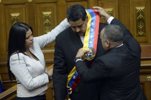 Maria Gabriela, hija de Chávez, y el presidente de la Asamblea Nacional Diosdado Cabello le colocan la banda presidencial a Maduro (AFP | juan barreto)