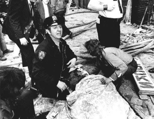 In this Jan. 24, 1975, file photo, a New York City police officer calls for help as he kneels near a victim of a bombing at the annex of Fraunces Tavern in New York. The leftist group Armed Forces of National Liberation, also known as FALN, claimed responsibility for the bombing that killed four people and injured more than 60.