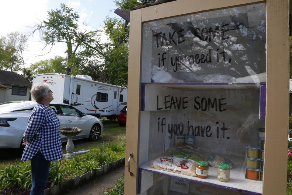 Cindy Robertson stands next to a pantry box she keeps stocked with items for homeless neighbors outside her home in Sulphur, La., on Wednesday, March 30, 2022. Robertson is worried about the impact of emissions from export facilities for liquified natural gas, or LNG. The export facilities are among the largest emitters of greenhouse gases in Louisiana, a state with heavy industrial pollution — and more are planned. (AP Photo/Martha Irvine)