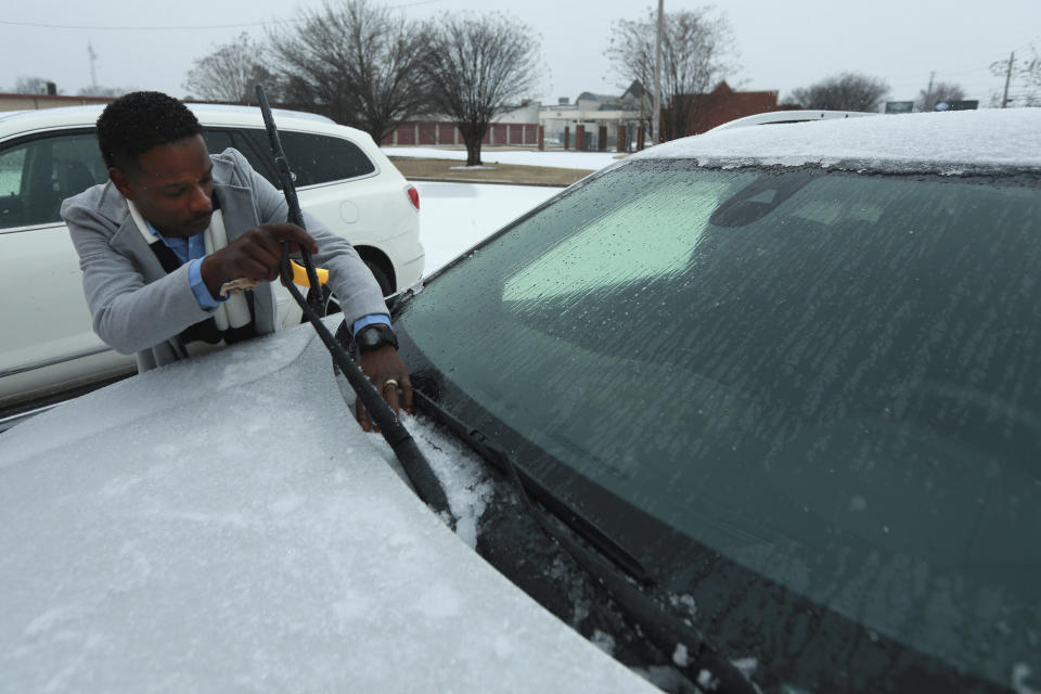 Mitra Bumphis, District Managet of KFC on West Main Street, cleans the base of his windshield to keep his wiper blades from freezing to the glass as he lets his car warm up at the West Main Street KFC early Monday morning in Tupelo. (Adam Robison/The Northeast Mississippi Daily Journal via AP)