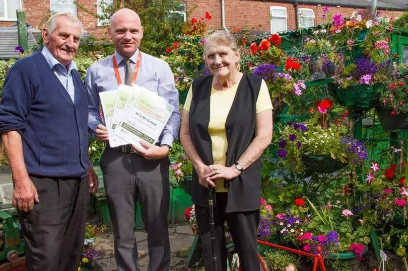 Julie’s mum and stepdad being presented with their certificates and shopping vouchers for garden centres in 2013
