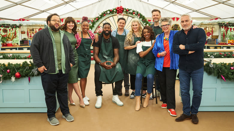 From left to right: Zach Cherry, Casey Wilson, Phoebe Robinson, DeAndre Jordan, Arturo Castro, Heather McMahan, Ego Nwodim, Joel MchHale, Prue Leith, and Paul Hollywood standing together