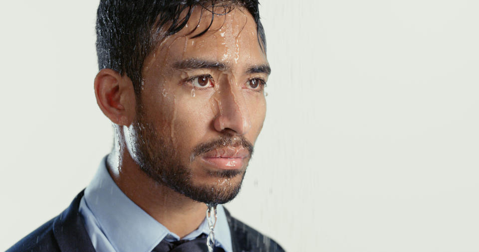 Man in a wet suit looking to the side, water dripping from his hair and face