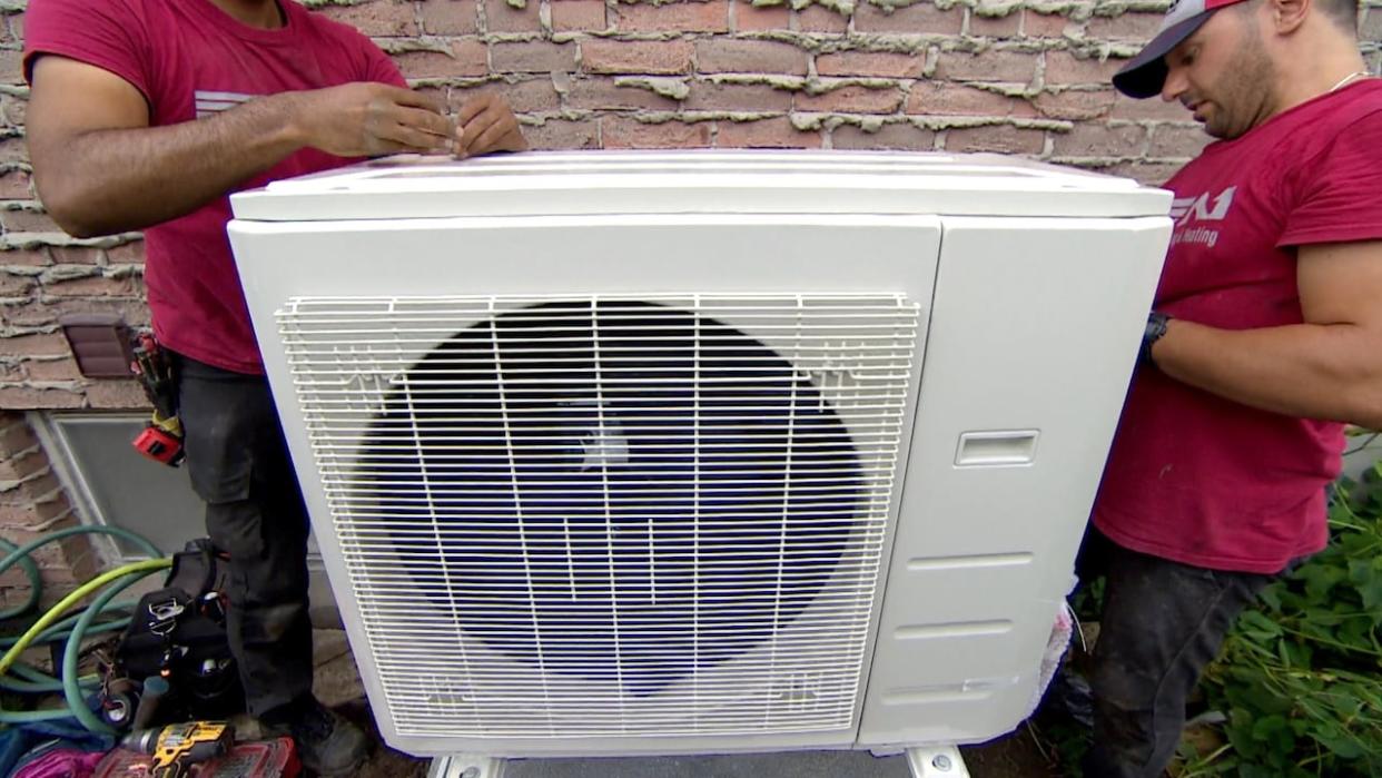 A new heat pump is installed at a home to replace both an old air conditioner and a natural gas furnace. (Spencer Gallichan-Lowe/CBC - image credit)