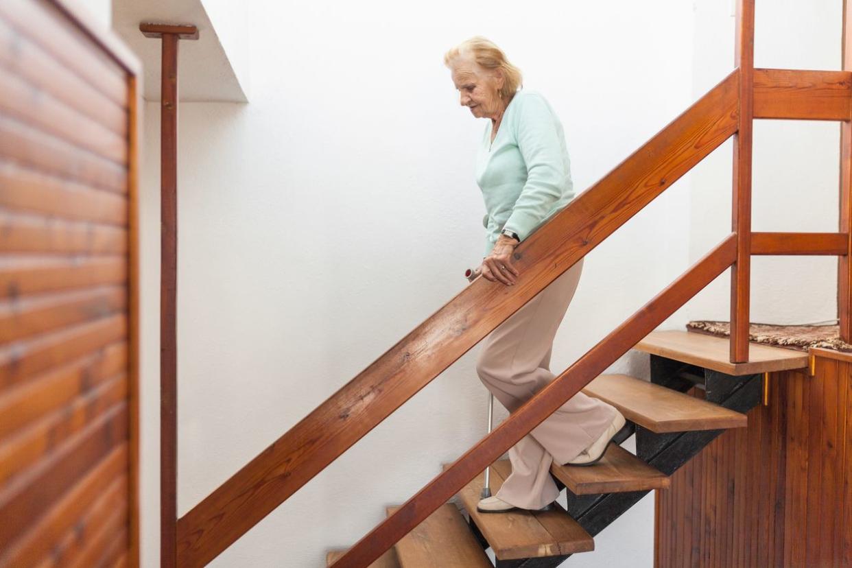 Senior nervously walks down stairs in need of a chair lift