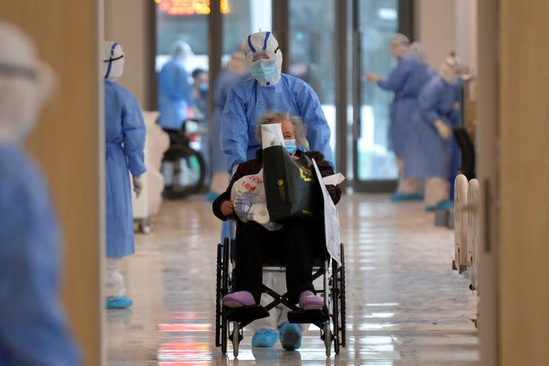 Medical worker in protective suit moves a novel coronavirus patient in a wheelchair at a hospital in Wuhan