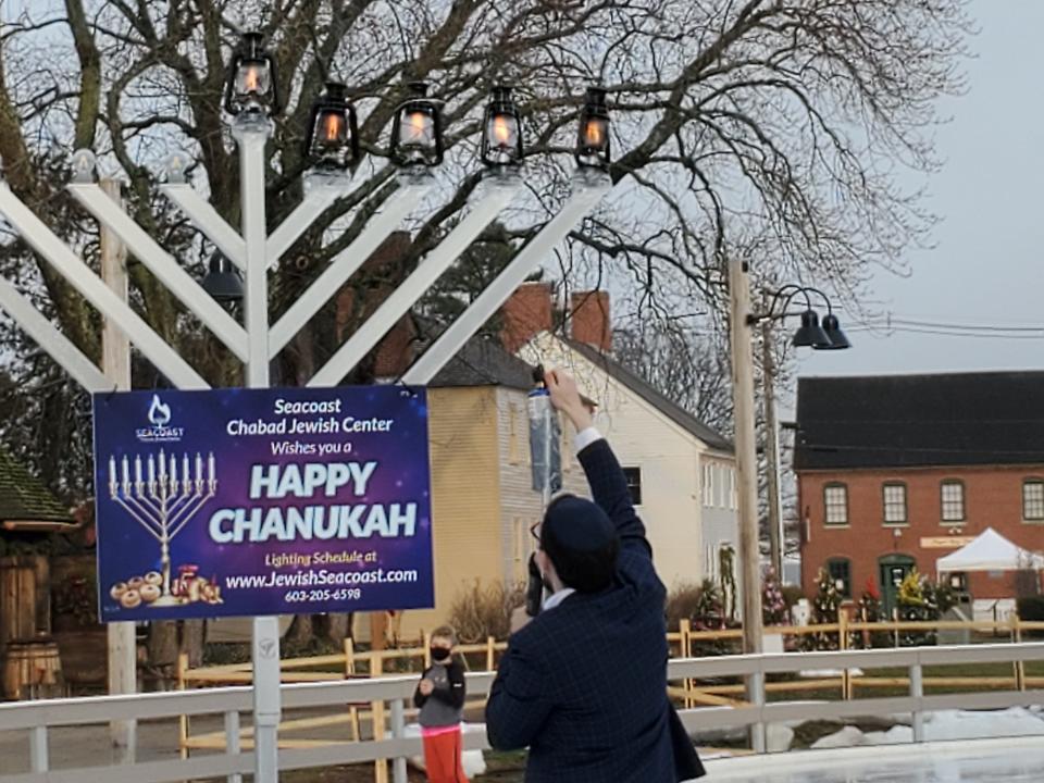 Rabbi Berel Slavaticki lights the menorah, set up on the ice at the Labrie Family Skate at Strawbery Banke during a past Hanukkah celebration. The lanterns protect the flames on the candles that have been lit.