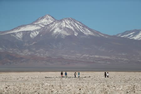 FILE PHOTO: Tourists walk on the Atacama salt flat near Cejar lagoon in the Atacama desert