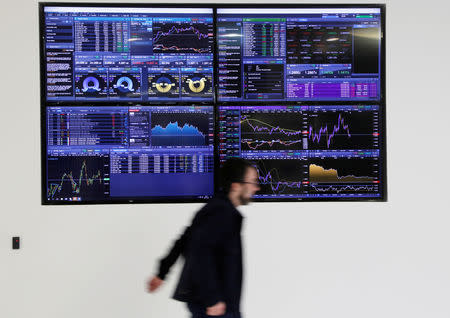 A man walks past screens displaying market data at CMC Markets in London, Britain, January 16, 2019. REUTERS/John Sibley