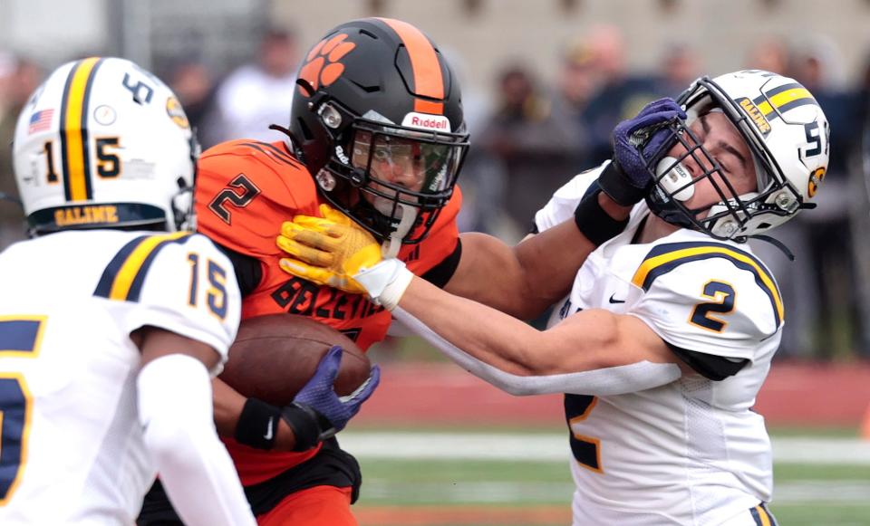 Belleville's Adrian Walker stiff arms Saline's Ryan Kavanaugh as he runs for extra yardage during first-half action in the MHSAA Division 1 District football championship game between Saline and Belleville at Bellville High School in Bellville on Saturday, November 4, 2023.