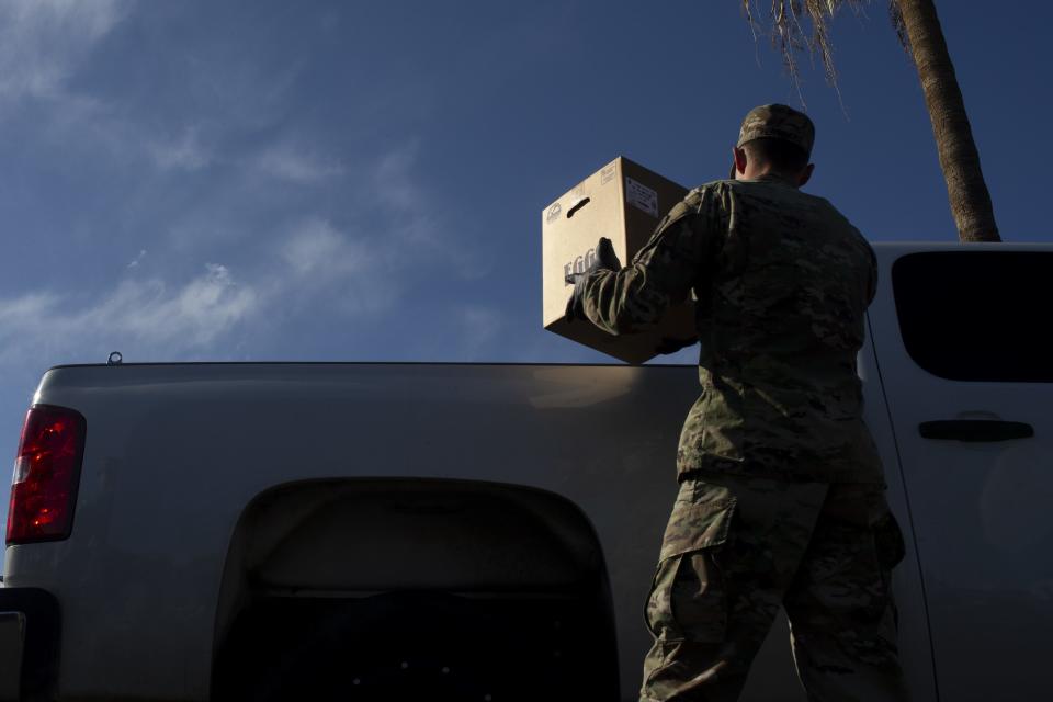 Volunteers with United Food Bank and members of the Arizona National Guard pass out food to those in need at the Mesa Convention Center in Mesa, Ariz. on March 27, 2020.