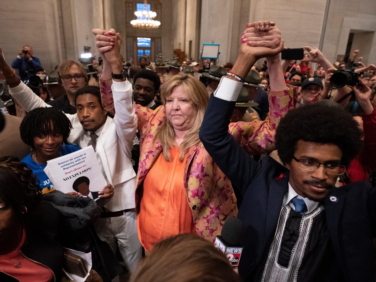 Former Rep. Justin Jones, D-Nashville, Rep. Gloria Johnson, D-Knoxville, and former Rep. Justin Pearson, D-Memphis,  join hands and hold them aloft amid a crowed of people. Pearson (right) and Jones (left) were expelled after protesting on the Tennessee house floor.