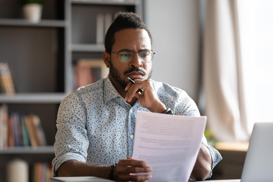 African student guy sit at desk hold papers tasks having difficulties with test, company lawyer read contract terms and detail feels discontented, received bad news from bank unpleasant letter concept