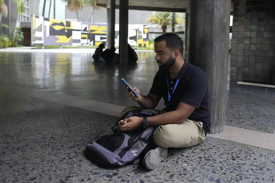 El estudiante Gabriel Ortiz utiliza su celular en la Universidad Central de Venezuela, en Caracas, el jueves 4 de julio de 2024. El hombre con el que salía Ortiz se marchó hace poco del país, donde la incertidumbre hace que muchos se pregunten si merece la pena iniciar una relación. (AP Foto/Ariana Cubillos)