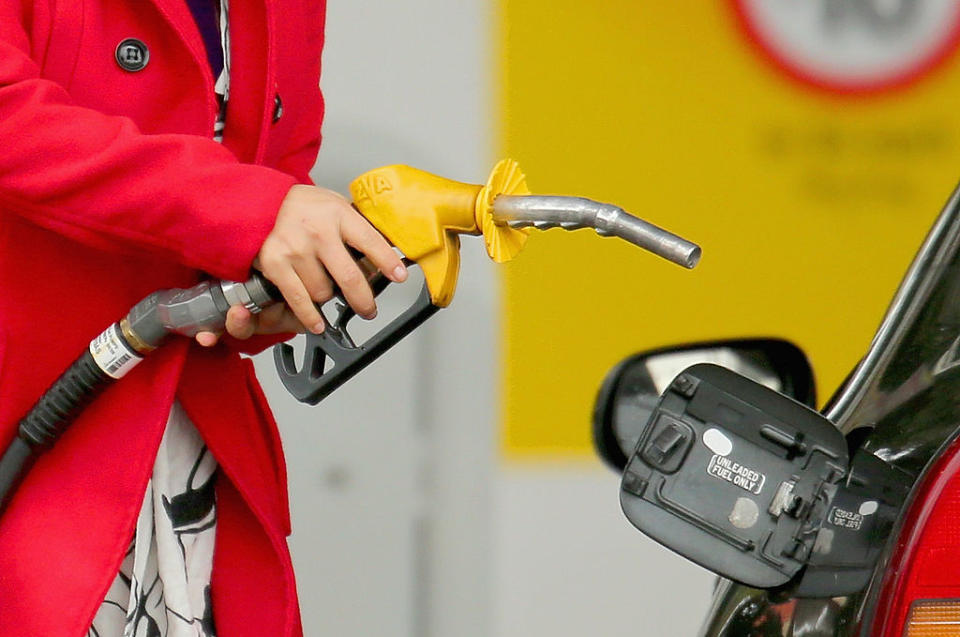 A woman uses a fuel dispenser to fill her car up with petrol at a petrol station on July 23, 2013 in Melbourne, Australia.