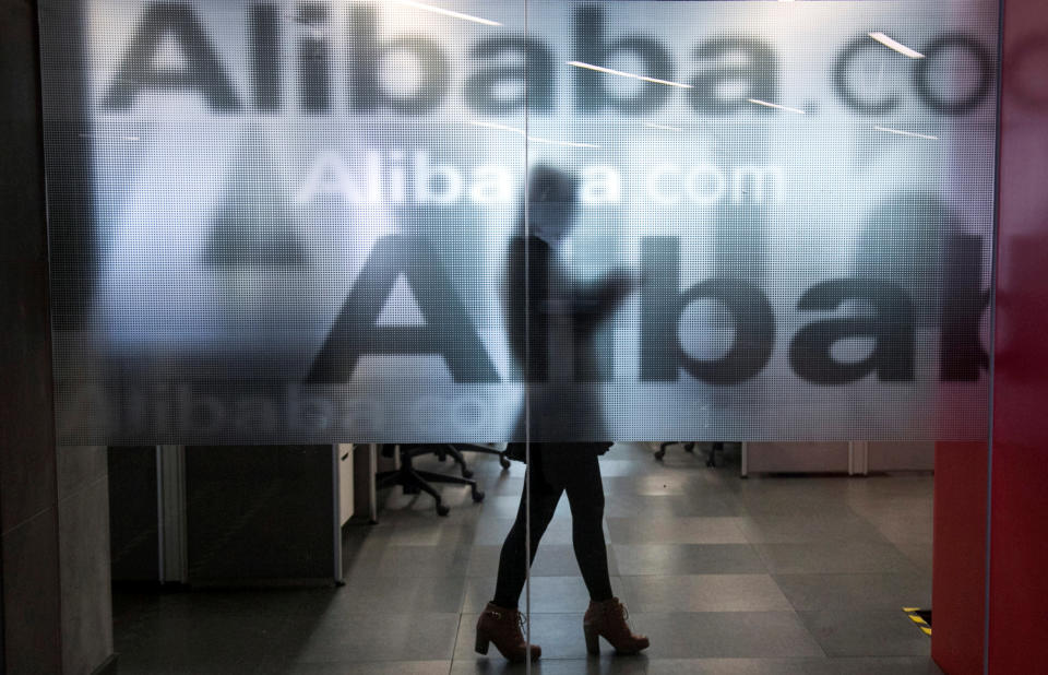 FILE PHOTO: An employee is seen behind a glass wall with the logo of Alibaba at the company’s headquarters on the outskirts of Hangzhou, Zhejiang province, April 23, 2014. REUTERS/Chance Chan/File Photo