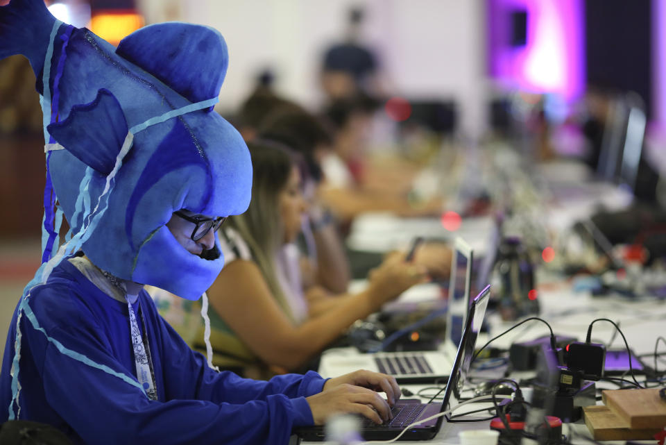 In this Feb. 12, 2019 photo, participants play games during the Campus Party technology festival, one in costume, in Sao Paulo, Brazil. Campus Party is an annual, week-long, 24-hour technology festival that gathers developers, gamers and computer enthusiasts. (AP Photo/Andre Penner)