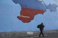 A man passes a mural showing a map of Crimea in the Russian national colours on a street in Moscow March 25, 2014. REUTERS/Artur Bainozarov
