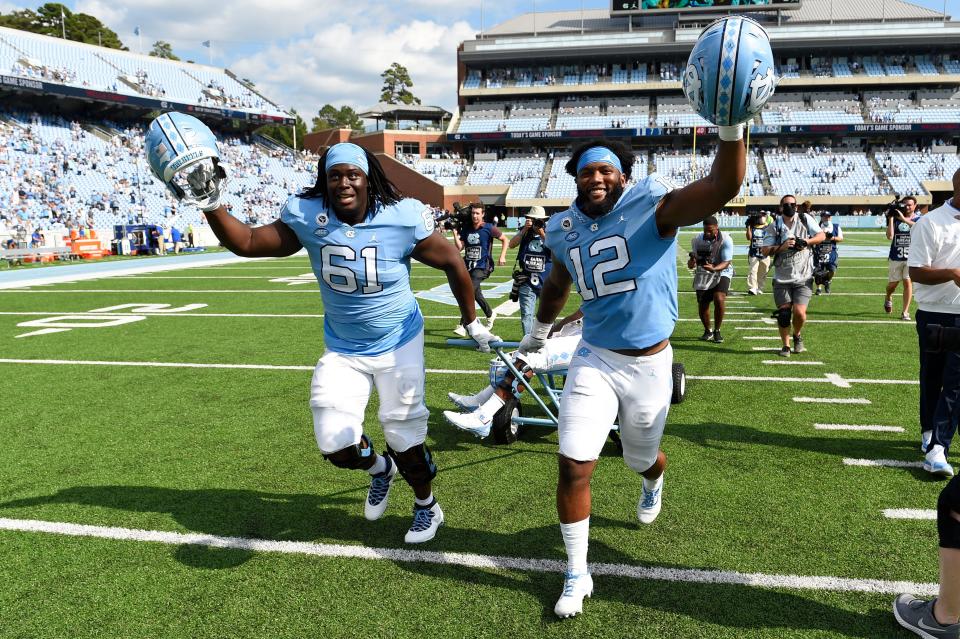 Offensive lineman Diego Pounds, left, and outside linebacker Tomon Fox, right, celebrate by pulling the Victory Bell after North Carolina’s blowout victory against rival Duke in October at Kenan Stadium.