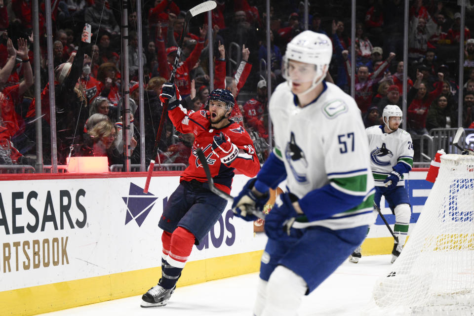 Washington Capitals right wing Nic Dowd, left, celebrates his goal during the first period of an NHL hockey game against the Vancouver Canucks, Sunday, Feb. 11, 2024, in Washington. Canucks defenseman Tyler Myers is at center and center Pius Suter is at back right. (AP Photo/Nick Wass)