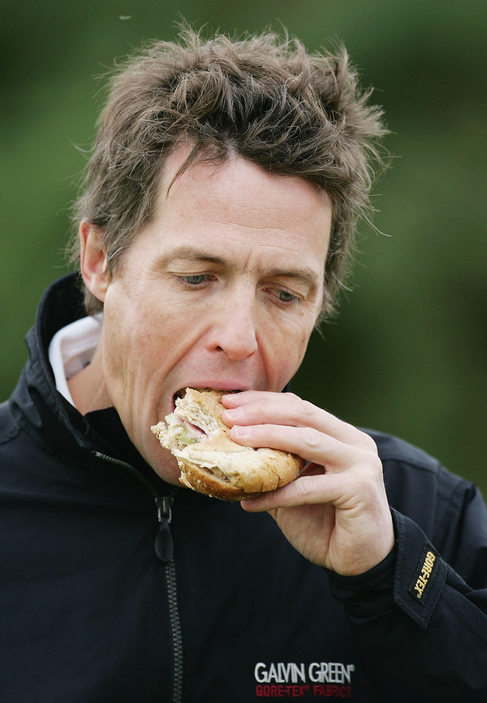 KINGSBARNS, SCOTLAND - OCTOBER 7:  Actor Hugh Grant eats a sandwich after the 9th hole during the first round of the Dunhill Links Championship at the Kingsbarns Golf Club on October 7, 2004 in Kingsbarns, Scotland.  (Photo by Ross Kinnaird/Getty Images)