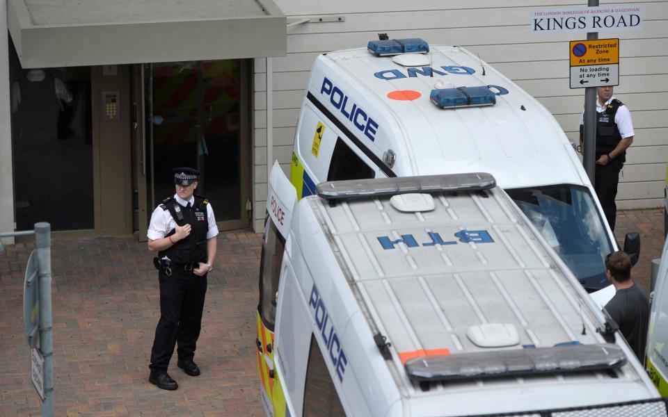 Officers and vehicles stand outside a block of flats that was raided by police in Barking, east London - Credit: REUTERS/Hannah McKay