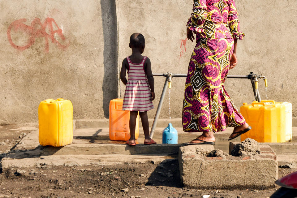 Una mujer y su hijo llenan contenedores en una bomba de agua en el centro de Goma,  la capital y ciudad más grande de la provincia de Kivu del Norte en la región oriental de la República Democrática del Congo (RDC) Foto de JUNIOR D. KANNAH/AFP vía Getty Images)