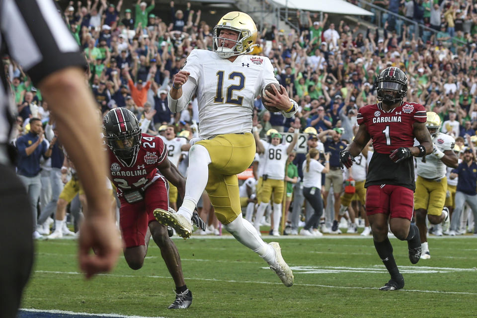 Notre Dame quarterback Tyler Buchner (12) crosses into the end zone for a touchdown during the first quarter of the Gator Bowl NCAA college football game against South Carolina on Friday, Dec. 30, 2022, in Jacksonville, Fla. (AP Photo/Gary McCullough)