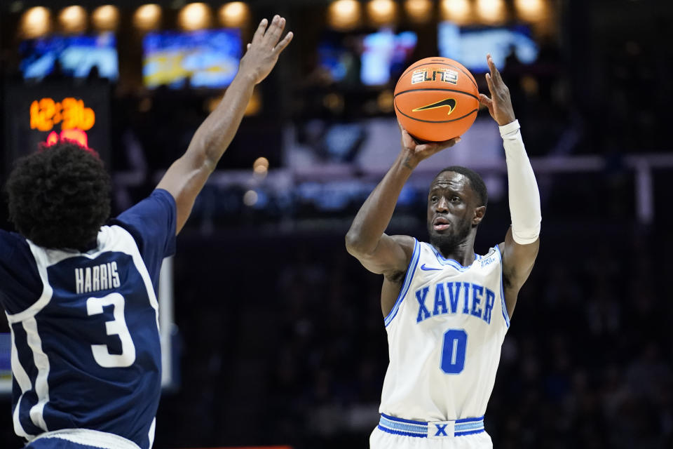 Xavier guard Souley Boum (0) shoots a 3-point basket as Butler guard Chuck Harris (3) defends during the first half of an NCAA college basketball game, Saturday, March 4, 2023, in Cincinnati. (AP Photo/Joshua A. Bickel)