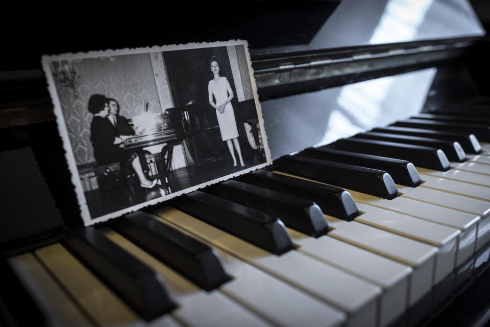 In this picture taken, April 26, 2020, a family album photograph showing Hannelore Fischer Cruz singing is placed on her piano at the house where she used to live in Braga, northern Portugal. Born amid the ruins of wartime Vienna, Hannelore Fischer was sent as a small child to Portugal where her flamboyant manner and outstanding soprano voice would later help her build a life far from her place of birth. She died of COVID-19 on March 25, 2020, after four days on a ventilator at Braga's hospital. (AP Photo/Luis Vieira)