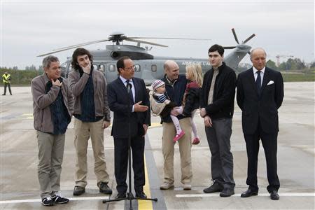 French Presidnt Francois Hollande (C) speaks with former French hostages and journalists, from L-2ndR, Didier Francois, Edouard Elias , Nicolas Henin, who holds his children, Pierre Torres and France's Foreign Minister Laurent Fabius (R), moments after their arrival by helicopter from Evreux to the military airbase in Villacoulbay, near Paris, April 20, 2014. REUTERS/Gonzalo Fuentes