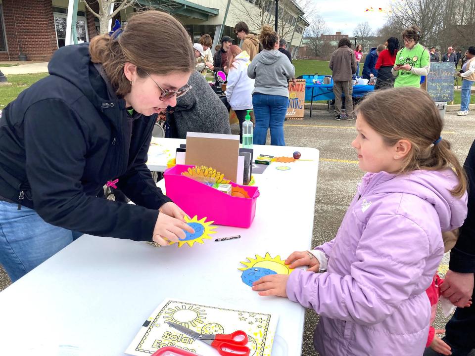 PennWest senior Madison Ekas helps Emersyn Mizikowski, 7, of Erie, make a paper eclipse in the student-led activities area at the university watch party.