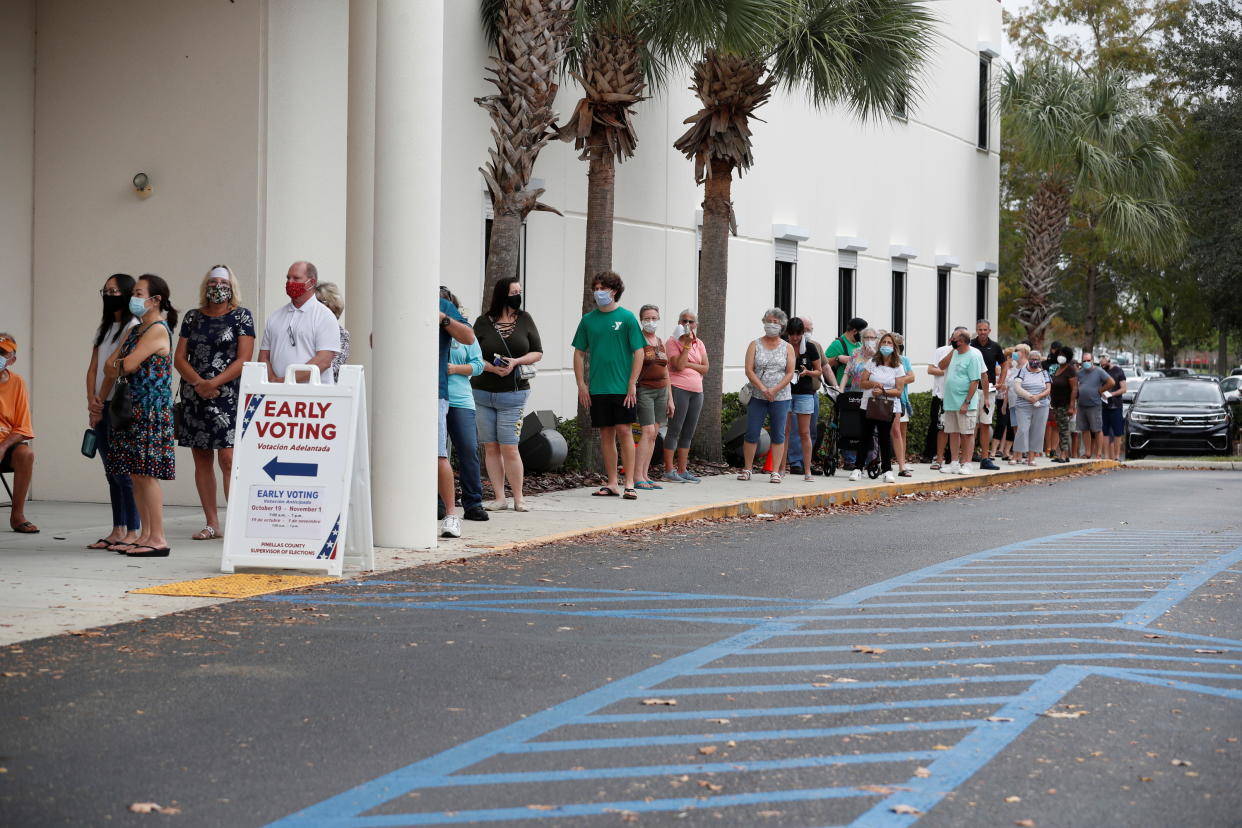 People line up at the Supervisor of Elections Office polling station as early voting begins in Pinellas County ahead of the election in Largo, Fla., Oct. 21, 2020.