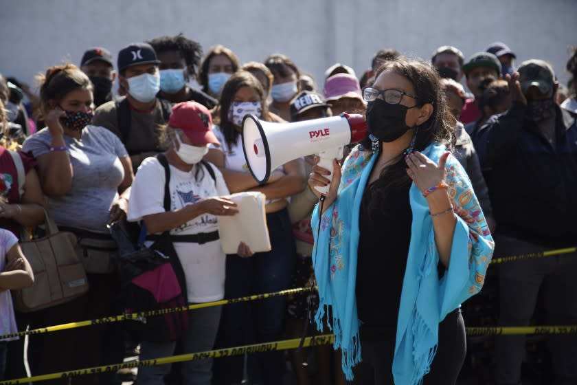 Tijuana, Baja California - May 13: Using a megaphone Dulce Garcia speaks to the group asylum seekers. She explains the process of who they will work with at Colonia Empleados Federales on Thursday, May 13, 2021 in Tijuana, Baja California (Alejandro Tamayo / The San Diego Union-Tribune)