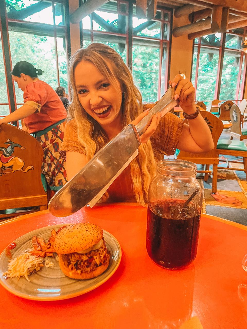 kayleigh pretending to eat a burger with a big knife at whispering canyon cafe