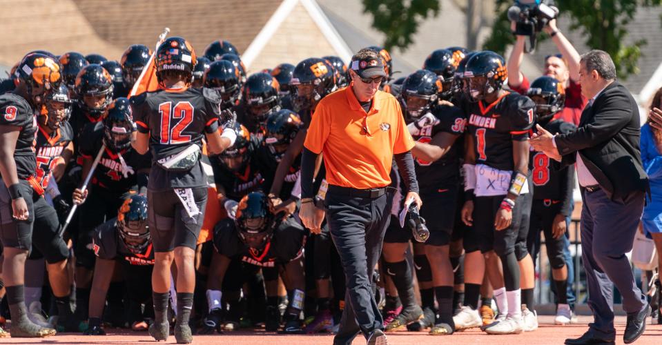 Head coach Al Chiola leads a somber Linden High School football team onto the field for their Sept. 24 game against Perth Amboy, just days after player Xavier McClain, 16, died after suffering an apparent head injury in a game on Sept. 9.