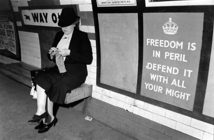 An unidentified woman knits on a bench in the underground train system, London, England, 1939